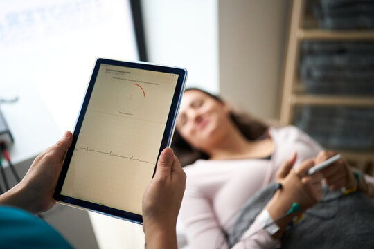 Physiotherapist monitoring neurostimulation treatment on a tablet
