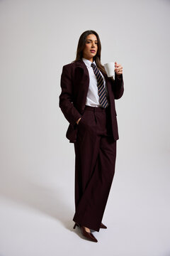 Businesswoman standing in formal attire with a cup in her hand