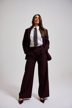 Woman in formal attire stands confidently during a studio shoot