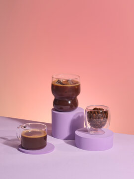 Three coffee drinks and beans displayed on purple pedestals