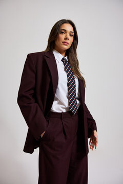 Model poses in tailored suit with tie in studio backdrop