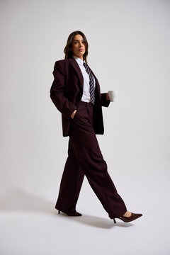 Business attire model walks with a cup in a studio setting