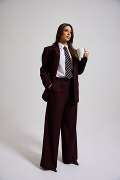 Business attire worn by a woman holding a cup in studio setting