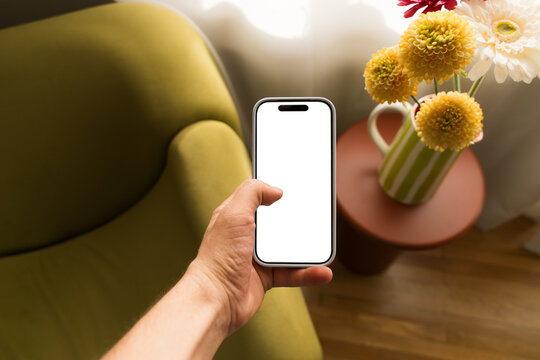 Modern smartphone in hand with empty screen on cozy setting