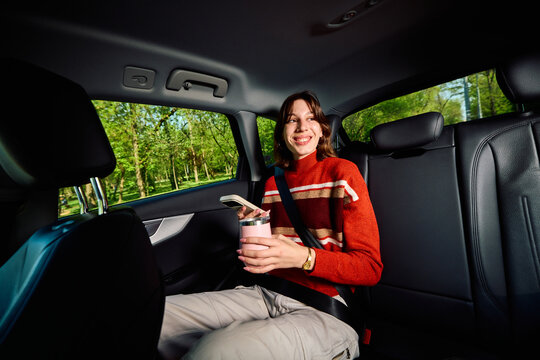 Happy woman rides in the backseat of a car.