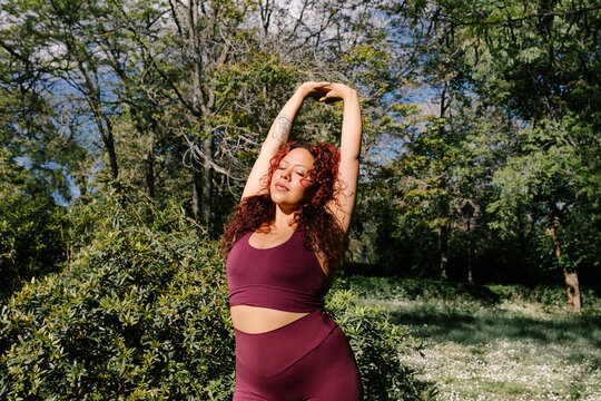 A plus-size athlete performs stretching movements in a park