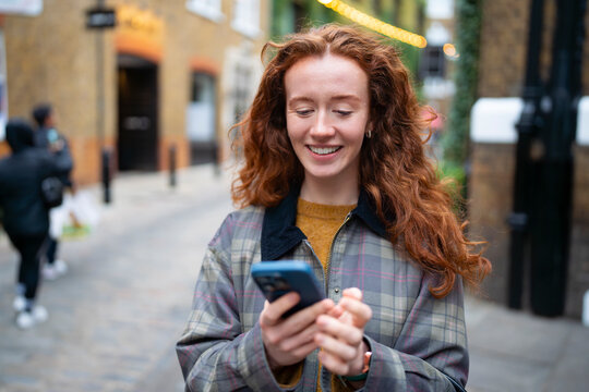 Smiling while reading message on smartphone in London