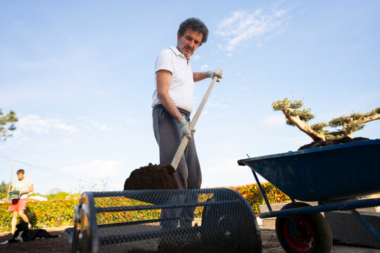 Shoveling soil into garden roller