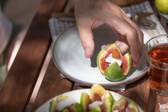 Fresh Figs on a Plate With a Hand Reaching for a Piece