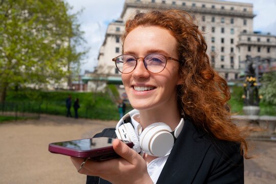 Woman smiling while using smartphone outdoors