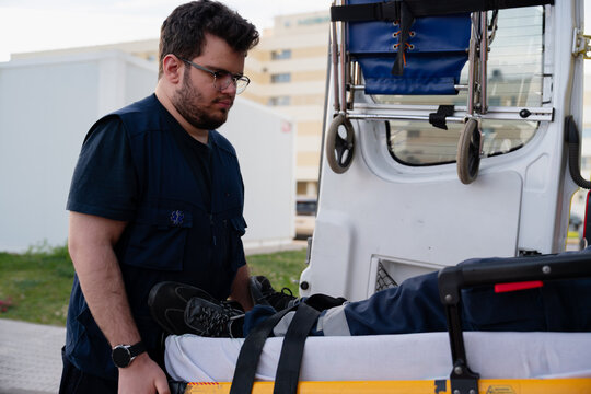 Paramedic loading patient on stretcher into ambulance