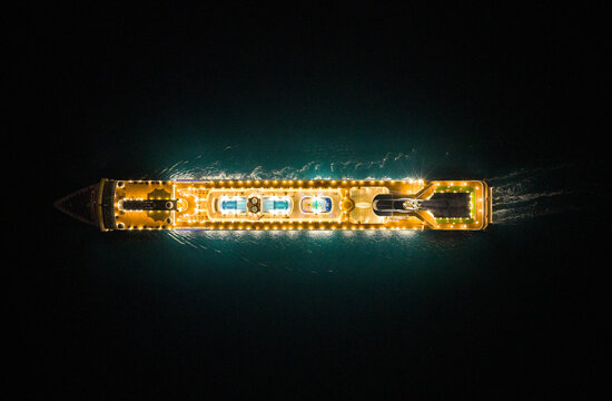 Top down drone shot of cruise ship with a brights lights at night