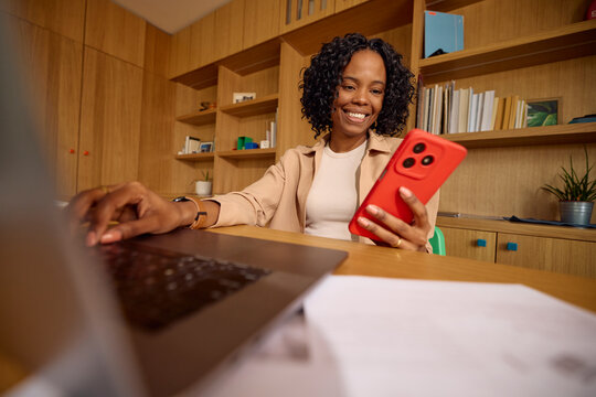 Attractive woman working from home, holding her mobile phone