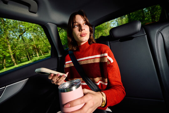 Casual woman is commuting in the backseat of a car