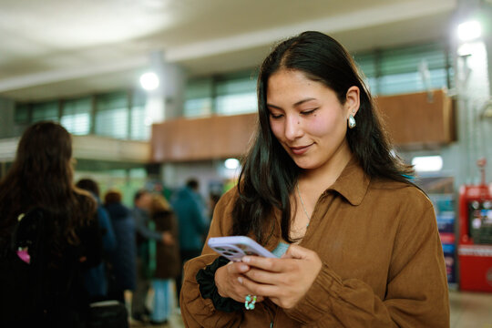 Latina woman using phone at station