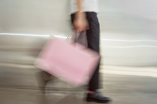 Person carrying a pink bag with motion blur.