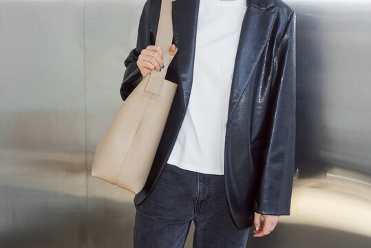 Woman wearing leather blazer and holding beige bag