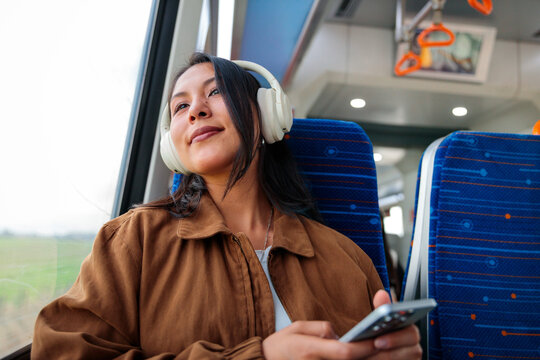 Woman with headphones using phone on train