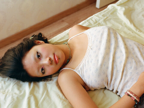Young Woman Lying on Bed in Soft Natural Light