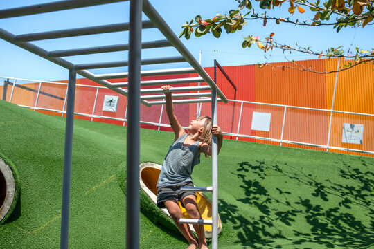 Child Reaching for Monkey Bars on Modern Playground