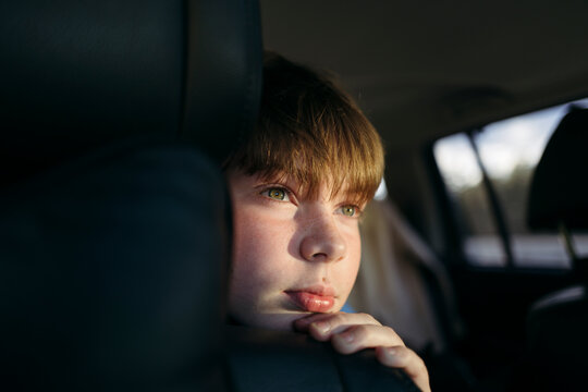 Boy Gazing Thoughtfully From Car Window During Golden Hour