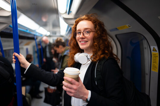 Smiling commuter holding coffee inside subway
