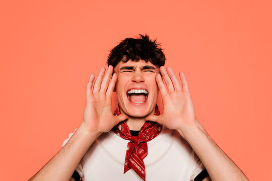 Man shouting desperately holding hands around mouth