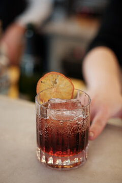 Anonymous holding cocktail on the bar counter