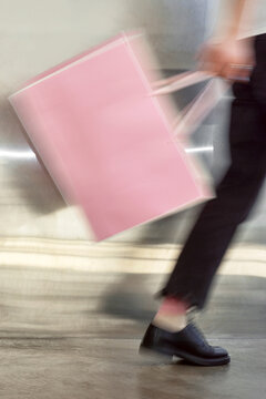 Person carrying a pink bag with motion blur.