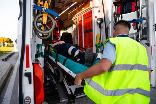 Paramedic loading patient on stretcher into ambulance