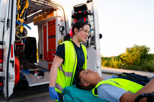 Paramedics moving patient on stretcher into ambulance