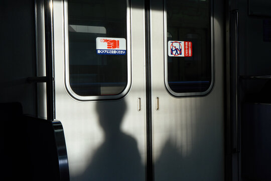 Silhouette of passenger inside subway train against closed doors.