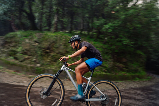 Biker Rides Through Wooded Path During Afternoon in Summer