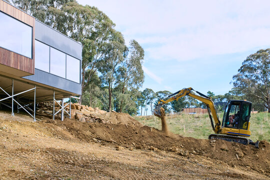 Excavator Working on Land Near a Home Under Construction
