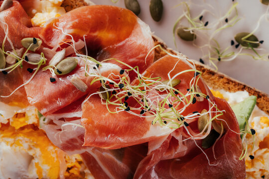 Gourmet toast with prosciutto, eggs, shoots and seeds