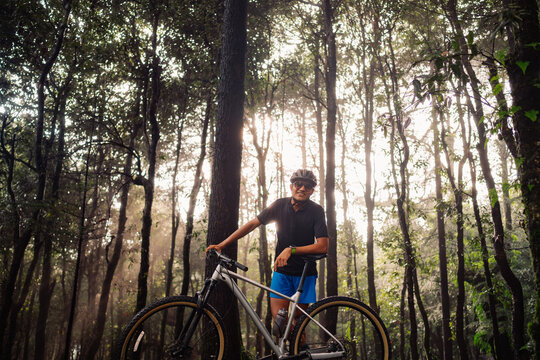 Cyclist Stands by Mountain Bike in Forest During Morning