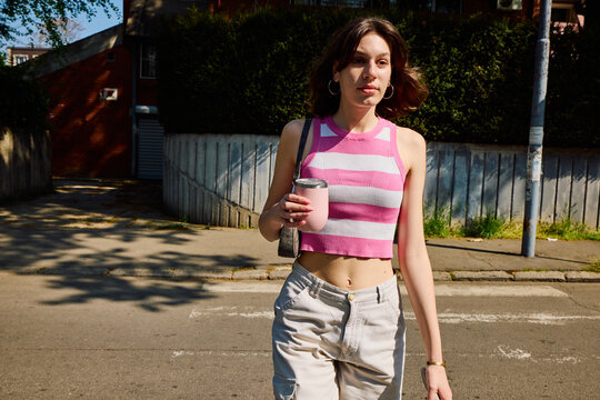 Casual  woman crosses the street, enjoys the sunny day