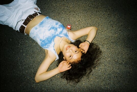 Lying on Asphalt with Toy Phone Necklace in Flash