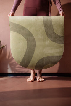 Woman Holding Yoga Mat in Minimalist Studio