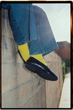 Legs dangling over concrete wall