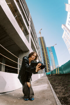 Young Person Takes Photos Near Construction Site in Bright Sunlight