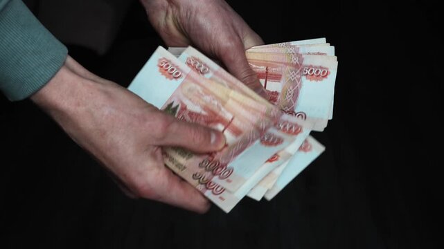 Man counts paper, 5000 rubles bills. Russian cash money in male hand. A man holds a wad of money in his hands. Russian Paper Money. Man counts a bundle of bills for five  thousand Russian rubles at th