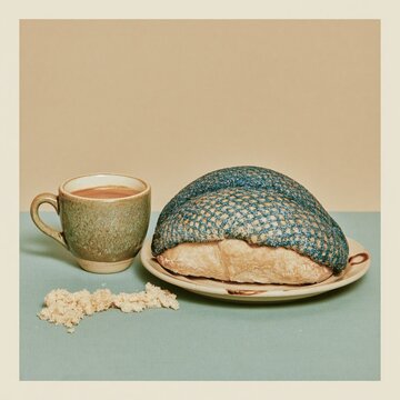 Mexican pan dulce concha with blue sugar topping sits beside a coffee cup on a minimal surface for bakery marketing, cafe menu design and breakfast food