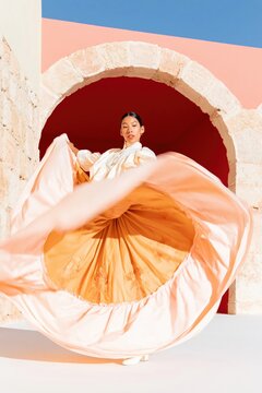 Pink spinning skirt of a young woman dancing in traditional folklorico dress under a stone arch for cultural events, travel promotion and latin heritage celebration