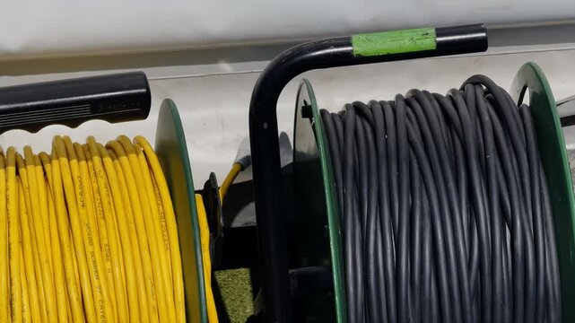 Close-up of coiled SDI, CAT5, and XLR cables on reels, showing professional broadcast wiring, production equipment, and organized media setup.