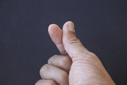 Close-up of a hand making a Korean finger heart sign isolated on a black background. symbolizing love and affection 