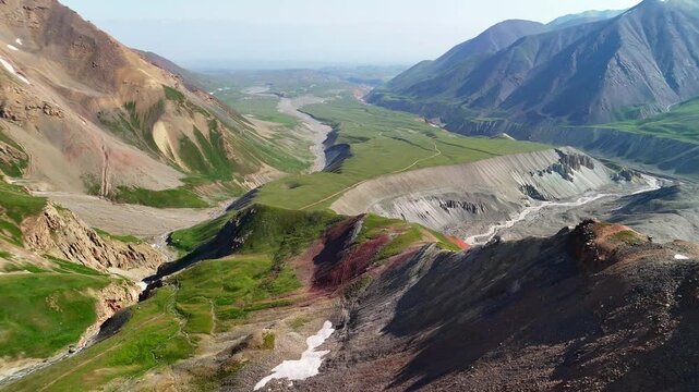 Aerial view of the Base Camp for Peak Lenin nestled in a vast mountain valley with winding streams and rugged peaks in Chong-Alay District, Osh Region, Kyrgyzstan.