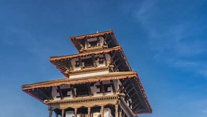 The roof of a Buddhist pagoda against a background of blue sky and clouds. Red frills along the cornices of the tiers, carved wooden beams, columns, arches. Nepal. Kathmandu. Durbar Square.    © Вера 