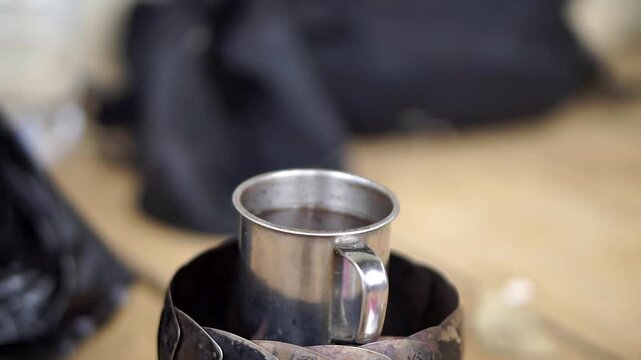 Close-up of a mini metal cup for boiling water or coffee with an aesthetic blurred background.
