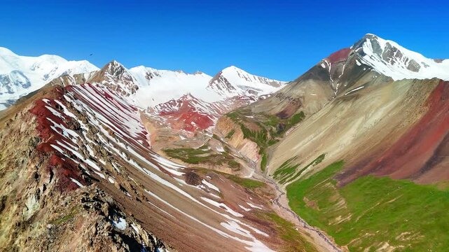 Aerial view of the Base Camp for Peak Lenin area featuring colorful mountain slopes and snow-capped peaks in Chong-Alay District, Osh Region, Kyrgyzstan.